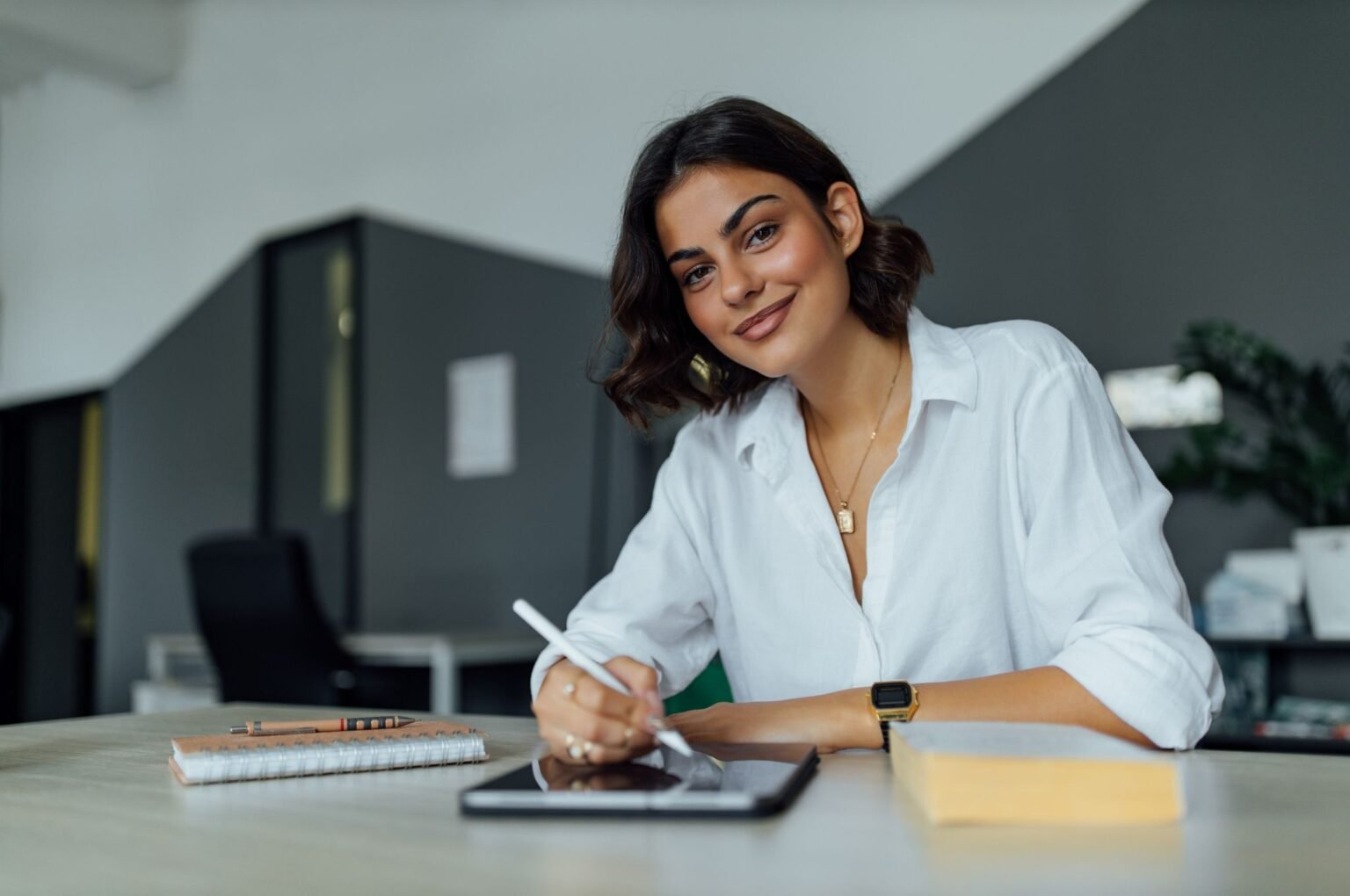 Ragazza sorridente che sta lavorando con l'iPad alla creazione di un sito web per creatori, imprenditori e aziende. - Innovative Web Agency