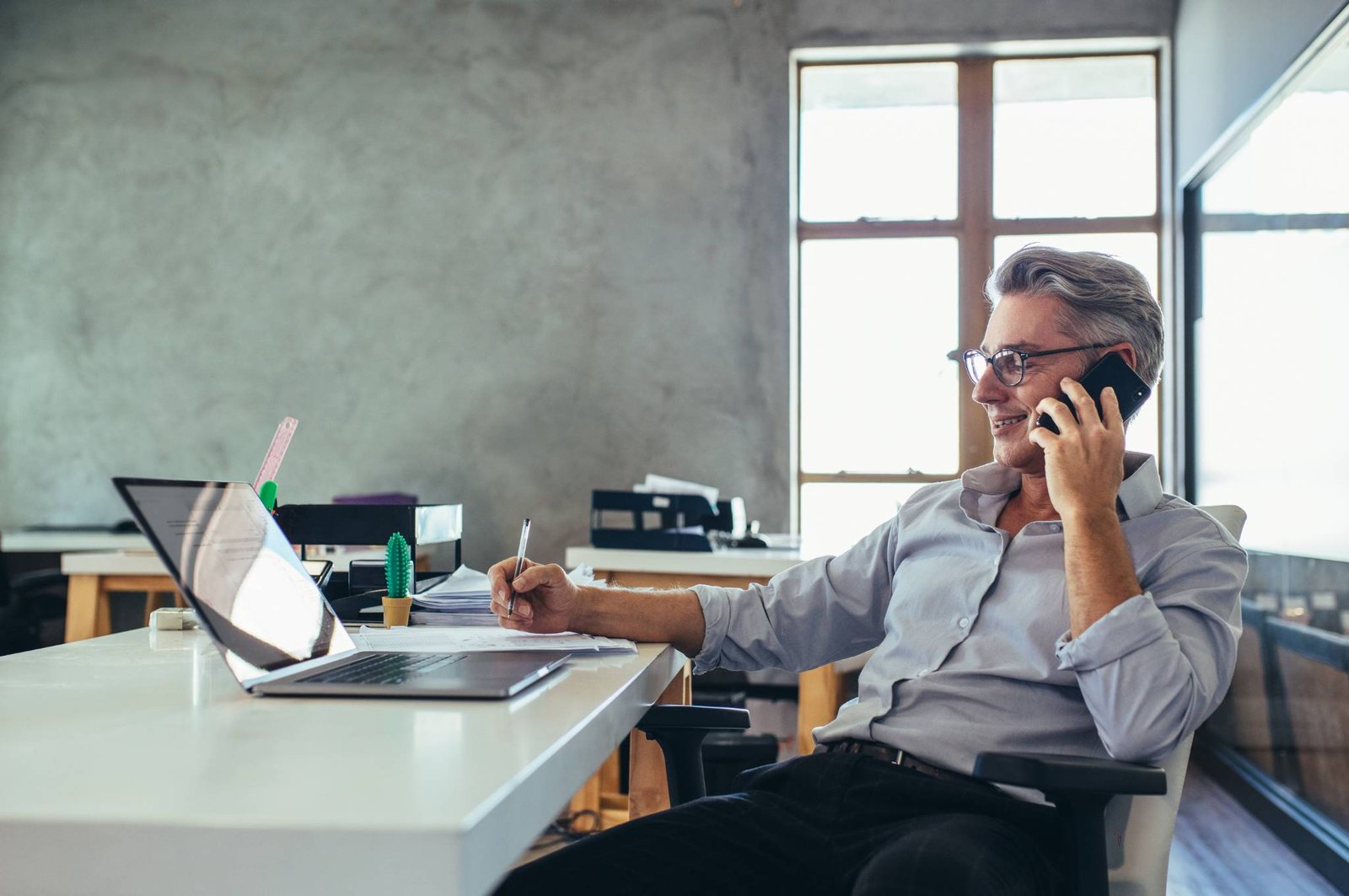 Professionista che parla al telefono e prende appunti con un cliente che chiede un sito web professionale.